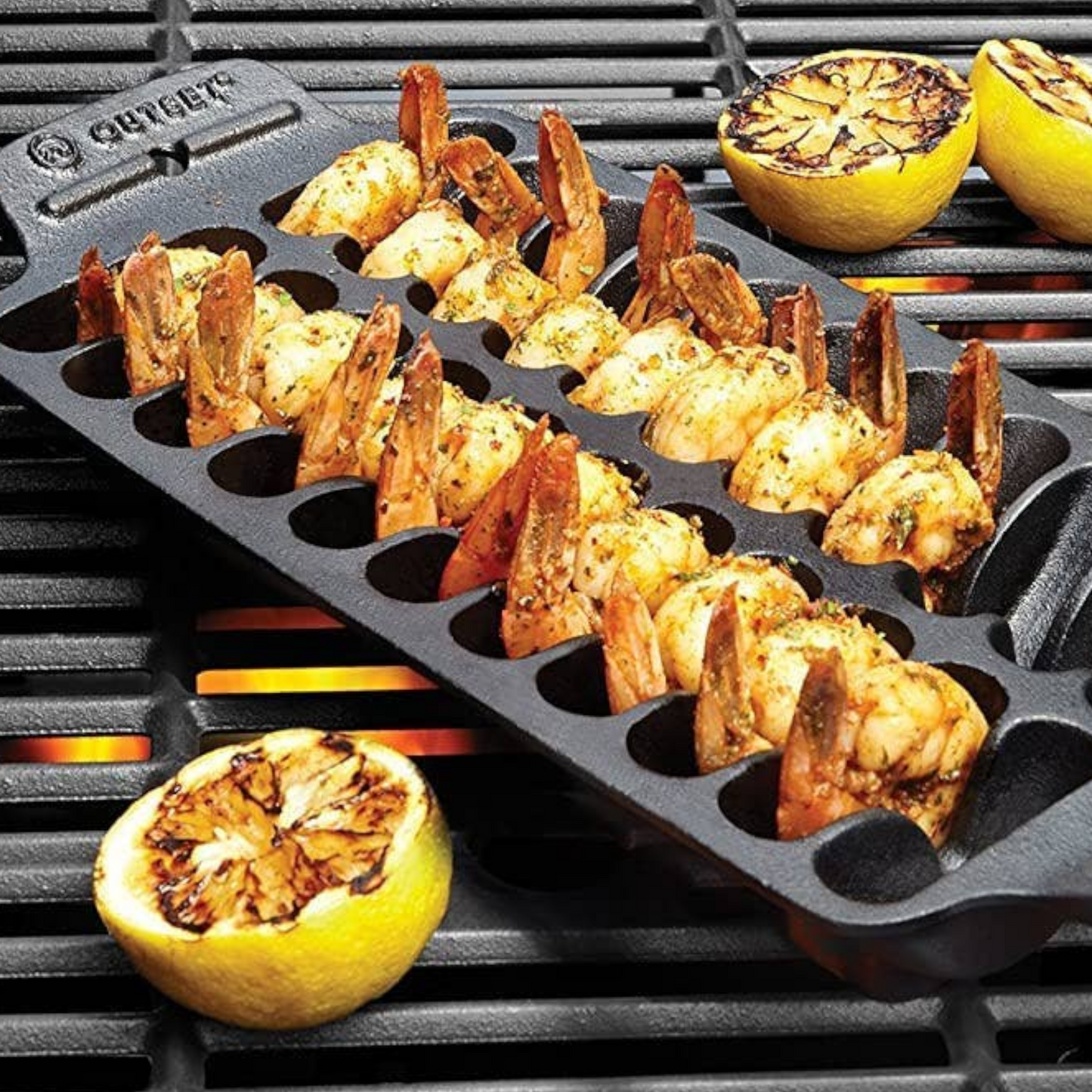 Cast iron skillet with 12 slots in each row holding grilled shrimp. Grilled lemons on the side for garnish.