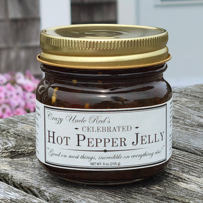 Jar of hot pepper jelly with a gold lid on a wooden surface