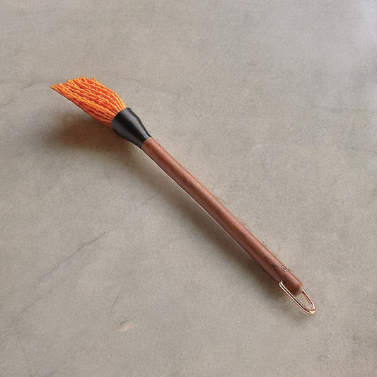 Wooden handles basting brush with orange silicone fringe on top.