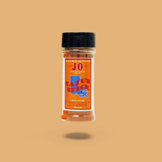J.O. Cajun Spice seasoning jar with rustic Southern spices on a neutral background