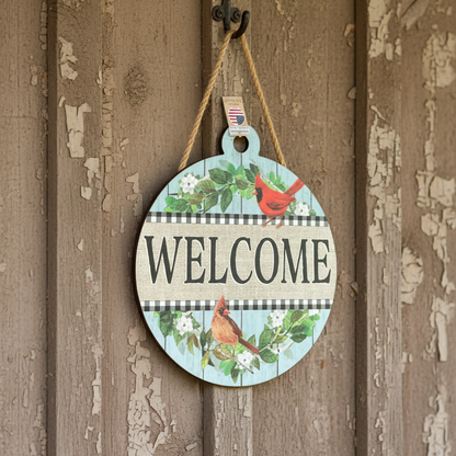 Round wooden sign with 'Welcome' text and cardinal birds hanging on a wooden door.