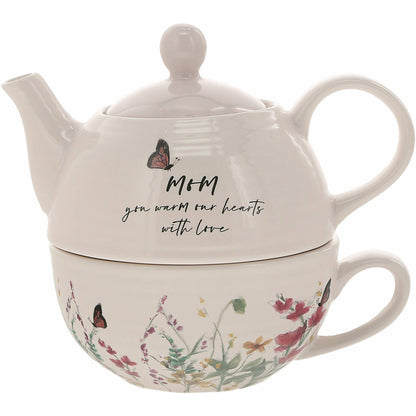 A beautiful Tea for One set featuring a 14.5 oz teapot with a pale pink lid and a 10 oz ribbed-texture cup, adorned with a floral design and the sentiment "Mom." Perfect for gifting to mothers on special occasions.