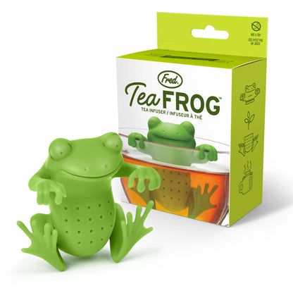 A green silicone tea infuser in the shape of a frog, with a mug in the background showing the product in use.