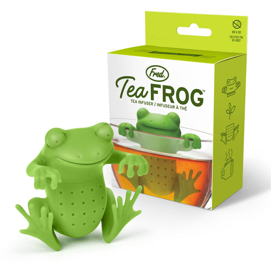 A green silicone tea infuser in the shape of a frog, with a mug in the background showing the product in use.